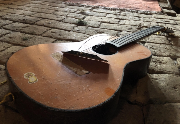 A broken guitar in an abandoned attic
