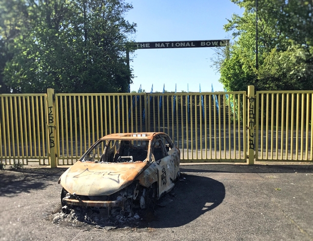 A burnt out car outside the National Bowl stadium Milton Keynes UK