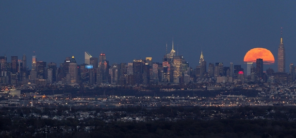 A full moon rises behind the New York City skyline - 