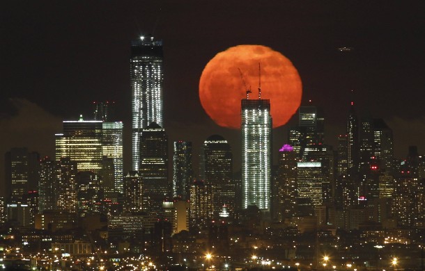 A full moon rises over the skyline of Lower Manhattan 