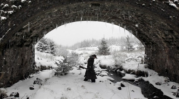 A hunter shelters under a bridge during a snow storm in the Glens of Antrim near Cargan Northern Ireland 
