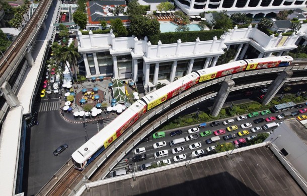 A skytrain passes over vehicles on the road in Bangkok Thailand 