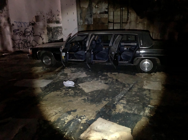 Abandoned Cadillac limousine inside of an decrepit store x
