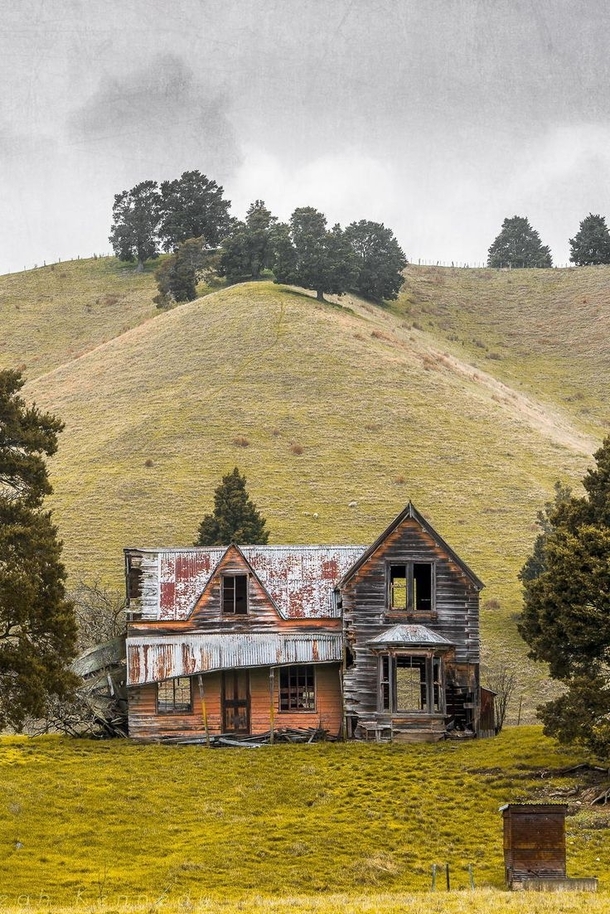 An abandoned decrepit house by a hill 
