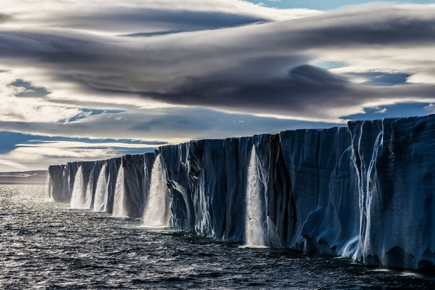 As our ship approached the massive ice cap I was shocked to see a string of waterfalls that straddled the entire expanse of the melting ice - Nordaustlandet Svalbard Norway  Photo by Paul Nicklen