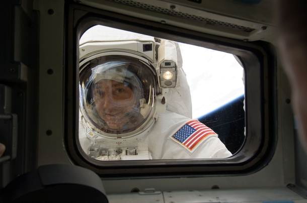 Astronaut Mike Massimino peers into Space Shuttle Atlantis aft flight deck window during STS- 