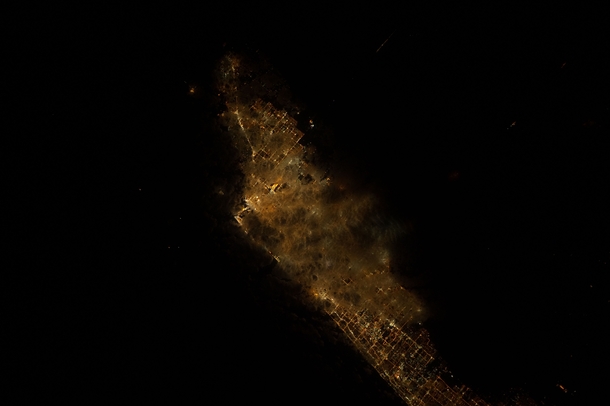 Cloud cover at night illuminated by unidentified city below Image taken by NASAs Earth Science and Remote Sensing Unit on the ISS 