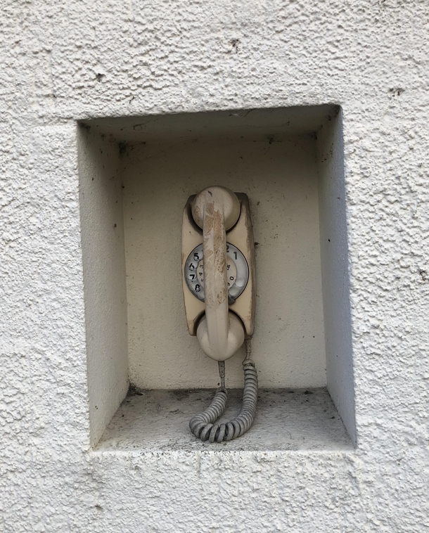 Curious abandoned telephone installed into the side of a building