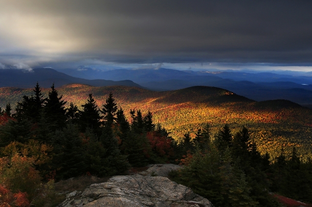 Fall foliage colors a line of mountains in Chatham New Hampshire as unsettled weather begins to clear on October 
