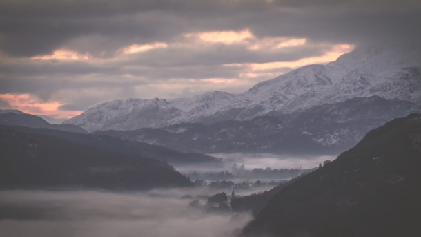 Fog snakes through a Scottish Highland valley in the last of the evening light 