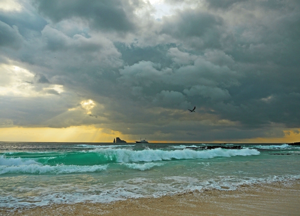 Glassy green waves and stormy sunset at Kicker Rock in the Galapagos 