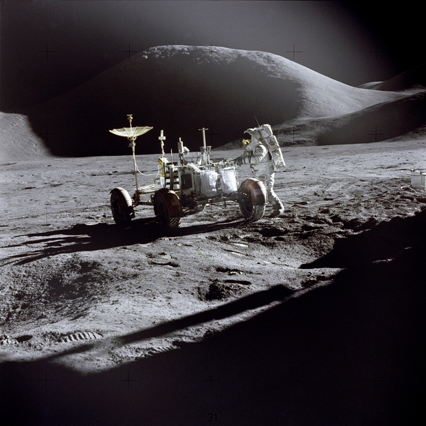 James Irwin works at the Lunar Roving Vehicle during the first Apollo  lunar surface EVA at the Hadley-Apennine landing site This view is looking northeast with Mons Hadley which has a height of  km and a maximum diameter of  km at its base in the backgro