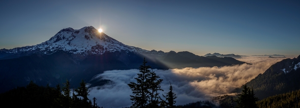 Light breaks from behind Mount Rainier and shines down on a sea of clouds - 