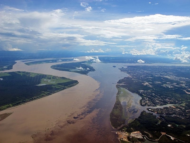 Meeting of waters - confluence between the Rio Negro almost black colored and the sandy-colored Amazon River or Rio Solimes 