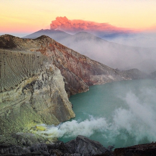 Mount Ijen smoking while Mount Raung erupts in the background at sunrise East Java Indonesia 