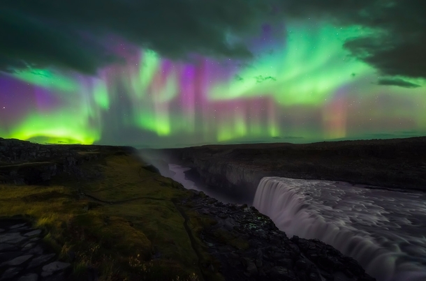 Multicolored Lights of the Aurora Borealis over Dettifoss a gigantic waterfall in Northern Iceland -  OC