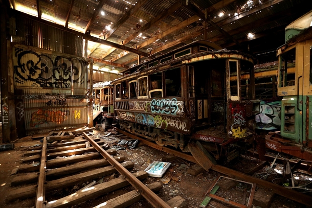 Old tramcars and trolley buses sit abandoned and wrecked in the Loftus Tram Shed in Sydney Australia 