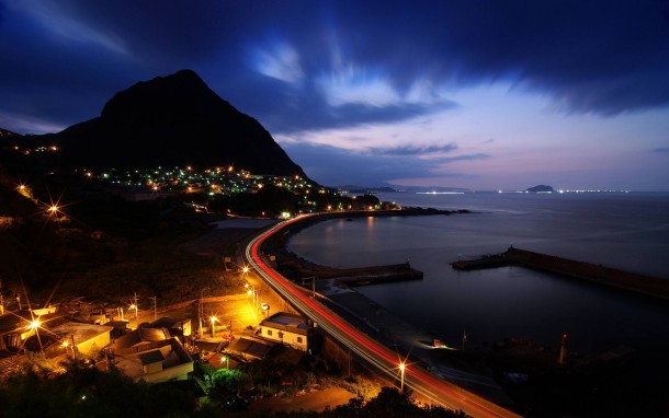 Some kind of Cove or Harbour at night with a mountain in the background -  Dark neon lights lens flares