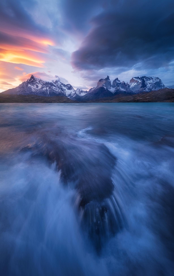 Stormy lakeside view with glowing lenticular clouds at sunset Torres del Paine NP Chile 