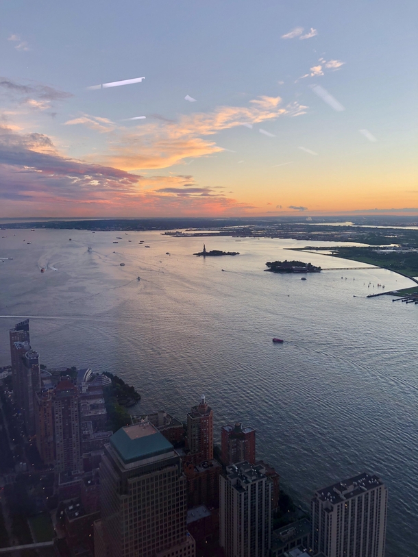 Sunset from the top floor of One World Trade Center overlooking the Statue of Liberty and NY harbor