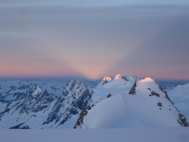 Sunset light V shining through mountain notch Combatant Col Mt Waddington BC Canada 
