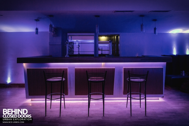 The bar of an abandoned nightclub illuminated by blue lights that still work 