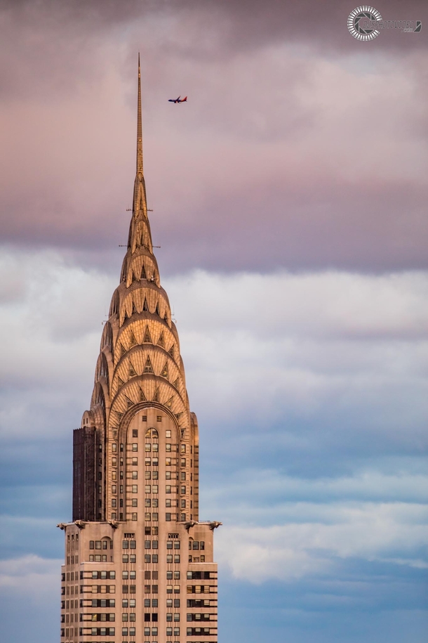 The Chrysler Building in NYC at sunset as a plane flies past 