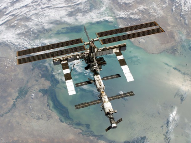 The ISS after being visited and resupplied by space shuttle Discovery orbiting above the Caspian Sea 