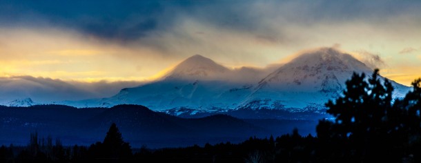 The Sisters Bend OR veiled in clouds and backlit by the setting sun Winter  