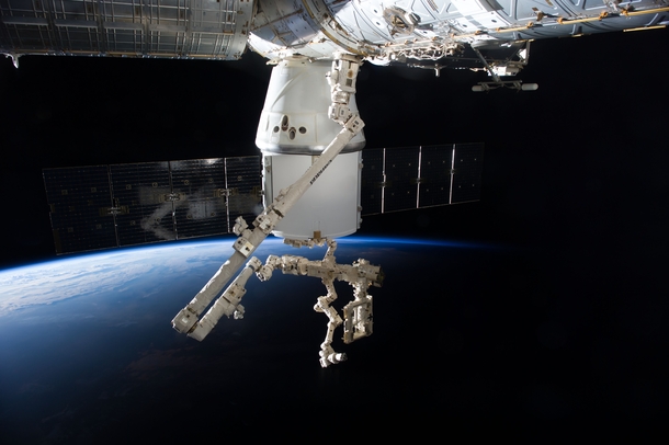 The SpaceX Dragon and the Canadarm with Earths horizon in the background 