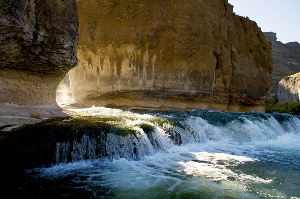 Water flows through the rock formations at Pillar Falls as the sun rises above the Snake River in Twin Falls Idaho 