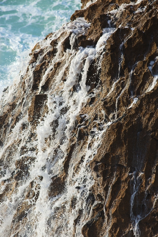 Water runs of a rock after being struck by a wave 