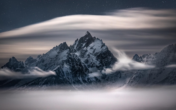 Waves of clouds swirling around the Teton Range on a moonlit night 