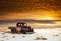 A beautiful sunset illuminating an old rusty prairie relic 