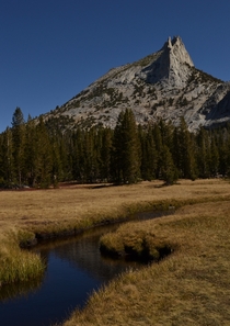 A calm stream leading to a jagged spire of granite Cathedral Peak Yosemite National Park CA  seanaimages
