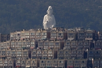 A -meter-high -foot Buddhist Avalokitesvara or Guan Yin statue part of the Tsz Shan Monastery stands behind luxurious houses at Tai Po District in Hong Kong Bobby Yip 