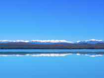 A slice of mountain cuts through the blue of sky and lake - Lake Pukaki New Zealand 
