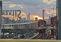 A  train moving into Queensboro Plaza with the Manhattan skyline in the background 