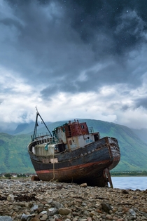 Abandoned black and red ship on shore 