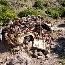 Abandoned car covered with rocks in Nijar National Park Almeria