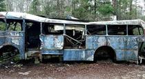 An abandoned bus in a car graveyard