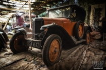 An abandoned old car among many other in a garage in the woods 