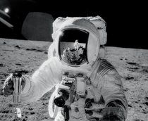 Apollo  lunar module pilot Alan Bean holds a container of lunar soil with the reflection of mission commander Charles Pete Conrad Jr visible on his visor