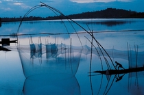At twilight on floodwaters from the Brahmaputra River a fisherman maneuvers a net on bamboo poles EPACorbis 