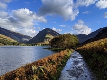 Buttermere lake in Lake District UK with grass and paths washed by the mountain springs all around 