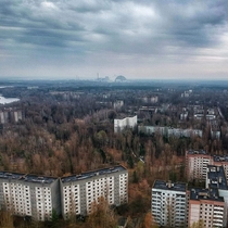 Drone shot over Pripyat and reactor  in the distance -
