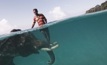 Elephant driver poses for a portrait while taking his elephant out for a swim info in comments 