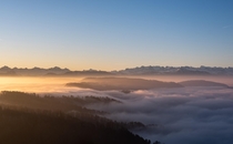 Fog slowly flowing over a chain of hills shortly after sunrise Zurich Switzerland 