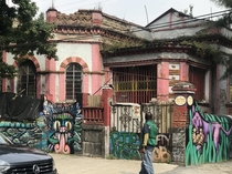 House starting to crumble grass growing on the roof with much graffiti in Coyocan Mexico City by Frida Kahlos house