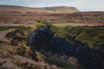 Hull Pot what remains of a cave with a collapsed roof with Pen-y-ghent looming in the distance Hull Pot Yorkshire Dales England 